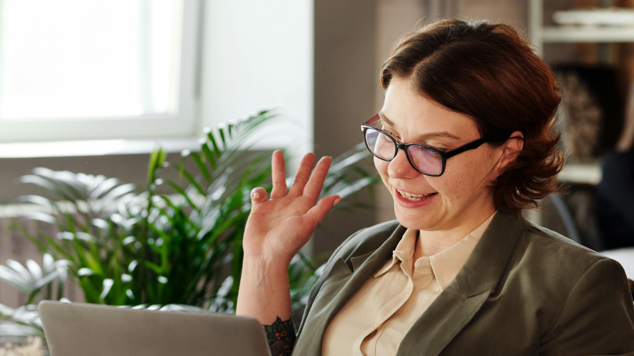 Woman looking happily at computer screen and waving